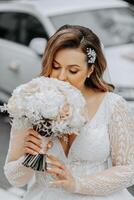 Portrait of a beautiful bride with a wedding bouquet of flowers, attractive woman in a wedding dress with a long veil. Happy bride woman. Bride with wedding makeup and hairdo. Winter wedding photo