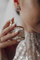 The bride holds perfume. Cropped photo, focus on perfume. Beautiful hands and manicure photo