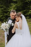 Wedding. Love and couple in garden for wedding. Celebration of ceremony and commitment. Save the date. Trust The groom embraces the bride in the mountains on the background of the forest photo