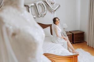 globos novia y un hermosa novia sentado en un cama en un lujoso tocador vestir preparando para el Boda ceremonia. foto