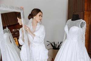 A beautiful brunette bride with a tiara in her hair is getting ready for the wedding in a beautiful robe in boudoir style. Close-up wedding portrait, photo. photo