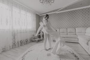 el novia en un seda traje y velo poses en su habitación. Mañana de el novia. preparación. Boda fotografía foto