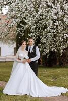 Wedding. Love and couple in garden for wedding. Celebration of ceremony and commitment. Save the date. Trust. The bride and groom embrace. The groom embraces the bride under a spring flowering tree. photo