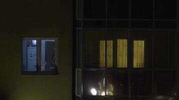 The view of the window where the man working behind the notebook. Young man working on computer at night in dark room video