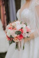 The groom hugs the bride, the bride holds a wedding bouquet. Cropped photo. Groom in a black suit. Details photo