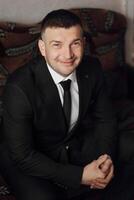 A man poses sitting on a chair. Portrait of the groom. Fashion and style. Business photo