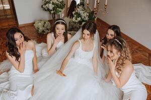 Friends rejoice with the bride in the morning. They take pictures, smile, help the bride fasten her dress. photo