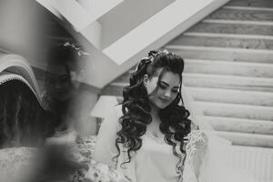 portrait of a luxurious bride in boudoir style near a mirror with reflection. Preparing the bride for the wedding in the morning in a white robe. photo