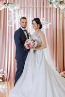 Wedding. Love and couple. Celebrating the ceremony and commitment. Save the date. Trust. The bride and groom embrace. Photo of a happy and bride and groom against the background of a ceremonial arch.