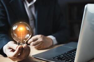 person hand holding power lightbulb and pretend to think, inspiration, creativity and imagination concept, innovation technology success business. Digital transformation. Ai technology. photo