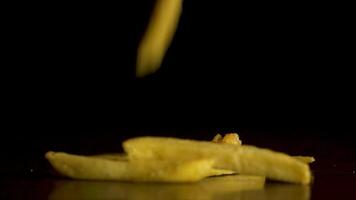 French fries fall on the table isolated on black background. Potato chips fall on the table isolated on a black background. Flying chips closeup. video