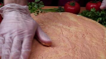 Adding sauce. Italian pizza preparation. Frame. Cheese being spread on tomato sauce on pizza base. Closeup hand of chef baker in white uniform making pizza at kitchen video