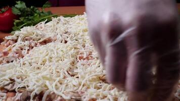 Adding sauce. Italian pizza preparation. Frame. Cheese being spread on tomato sauce on pizza base. Closeup hand of chef baker in white uniform making pizza at kitchen video