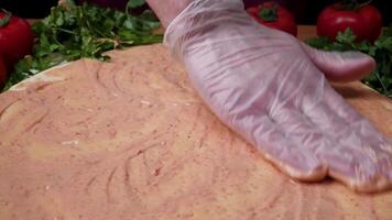 Closeup hand of chef baker in white uniform making pizza at kitchen. Frame. Cooking pizza. the workpiece poured tomato sauce. Chef sprinkles cheese pizza, a lot of cheese on a pizza, cooking process video