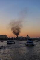 Cruise ship sails on the Moskva river, fire and smoke in the city centre of Moscow. photo