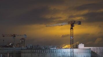 grúas a un construcción sitio trabajo a noche. hora lapso video