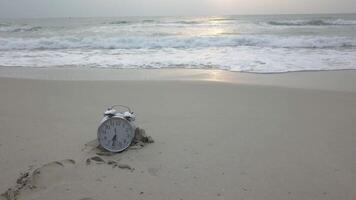 Ferien Zeit. Alarm Uhr auf das Sand. Video. Uhr das Strand. Uhr Lügen im das Sand auf das Meer symbolisieren ein Zeit von sich ausruhen video