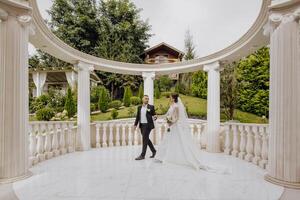 un caminar de hermosa y sonriente novias en su Boda día en un maravilloso lugar. en contra el antecedentes de alto columnas en el romano estilo. foto