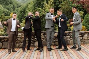 alegre, joven, energético testigos de el novio siguiente a el novio. amigos felicitar el novio. novio y su gracioso amigos teniendo divertido en el Boda día de el recién casados. foto