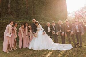 full-length portrait of the newlyweds and their friends at the wedding. The bride and groom with bridesmaids and friends of the groom are having fun and rejoicing at the wedding. photo