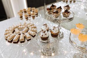 Candy bar for a wedding. Candy bar standing festive table with desserts, cupcakes and macarons. Beautiful and tasty. photo
