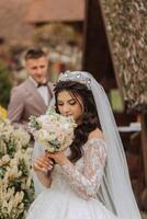 A beautiful young bride, in a summer park, walks ahead of her groom. Beautiful wedding white dress. Walks in the park. A happy and loving couple. photo