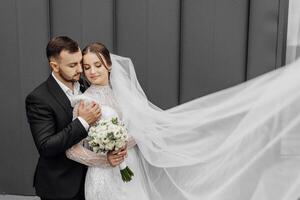 el hermosa novia suavemente abrazos el acicalar, quien abrazos su por el espalda. Boda concepto. el belleza y sensibilidad de un hombre y un mujer foto