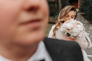 The bride and groom are walking near the hotel and posing, happy and enjoying the day, holding hands. A long train on the dress. Winter wedding photo