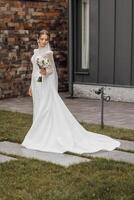 full-length portrait of a young bride in a white wedding dress with sleeves. Professional hairstyle and natural make-up. Wedding concept photo