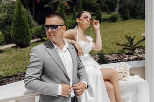 frio novia y novio teniendo divertido y vistiendo Gafas de sol al aire libre en soleado clima foto