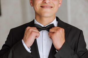 un elegante novio es atadura su atar, preparando para el Boda ceremonia. del novio Mañana. un empresario usa un atar. el novio es consiguiendo Listo en el Mañana antes de el Boda ceremonia. foto