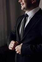 A man poses and fastens a black jacket. Portrait of the groom. Fashion and style. Business photo