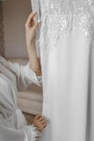 An exquisite wedding dress hangs on a chandelier in the bride's room. Morning of the bride. Preparation for the wedding. photo