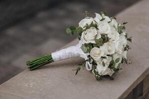 Portrait. The bride in an elegant long dress and veil, holding a bouquet, posing near a wooden railing. Wedding in nature photo