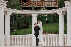 The bride and groom embrace near the Roman-style columns. An exquisite wedding photo