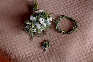 a rustic wedding bouquet of various flowers and greenery, the groom's flower and the bride's tiara made of flowers and green leaves. photo