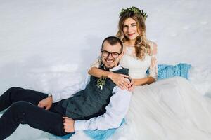 joven hombre y mujer corriendo acostado en nieve, reír, engañando alrededor, teniendo divertido jugando bolas de nieve europeo invierno boda. retrato de el novia y novio en el nieve foto