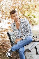 Vertical close-up portrait of a teenager in casual clothes. Happy smiling teenager in autumn park in sunlight. A beautiful child looks at the camera in nature. photo