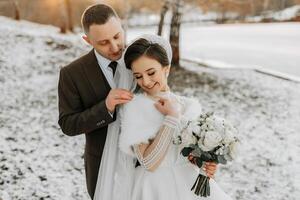 Wedding portrait of the bride and groom. Winter walk in nature. The bride embraces the groom, looking at each other. photo