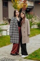 Vertical photo of two teenage friends dressed in casual clothes standing next to each other against a background of nature. Best school friends are ready to overcome anything to achieve the goal.