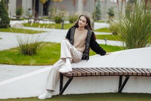 Vertical photo. Beautiful carefree young teenage girl in casual clothes. Portrait of a beautiful girl against the background of nature with a blurred background. photo