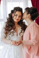 A beautiful and happy mother and her daughter, the bride, are standing next to each other. The best day for parents. Tender moments at the wedding. photo