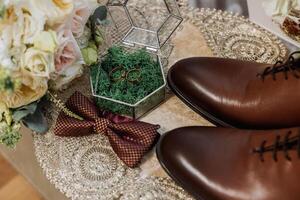 Men's accessories, groom details. Beauty is in the details. Preparation for the Wedding. Leather shoes. Gold wedding rings. Bow tie. Wedding bouquet of flowers. photo