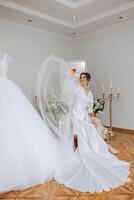 un hermosa morena novia es consiguiendo Listo para el Boda en un hermosa tocador estilo atuendo sentado en un silla entre Fresco flores y elegante candelabros Boda retrato, foto. foto