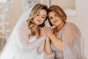 A beautiful and happy mother and her daughter, the bride, are standing next to each other. The best day for parents. Tender moments at the wedding. photo