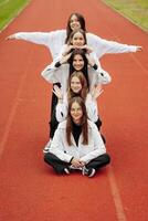 A group of smiling and happy teenage friends, dressed in casual clothes, spend time together, pose and have fun on the grounds of an educational institution on an autumn day. photo