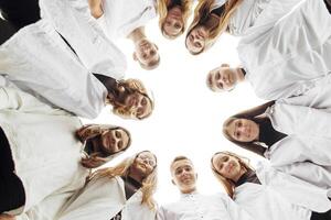 Large group of smiling young people standing, hugging, looking at camera. Group of cheerful teenage people in a circle looking down. Low viewing angle. Copy space. photo