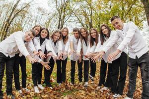 friendship, movement, action, freedom and people concept - group of happy teenagers or school friends posing and having fun outdoors against nature or forest background. photo