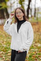 Vertical photo. Beautiful carefree young teenage girl in casual clothes. Portrait of a beautiful girl against the background of nature with a blurred background. photo