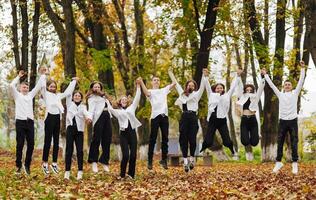 friendship, movement, action, freedom and people concept - group of happy teenagers or school friends posing and having fun outdoors against nature or forest background. photo